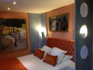 a bedroom with a bed with two pictures on the wall at L'Hôtel Le Cheval Noir in Moret-sur-Loing
