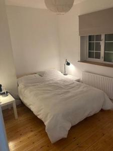 1 dormitorio con 1 cama blanca grande y escritorio en Entire Terraced two story redbrick house with parking in secluded cul de sac en Dublín