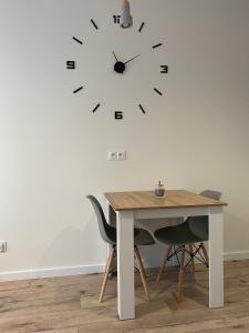 a table with chairs and a clock on a wall at Apartment Insat II in Szczecin