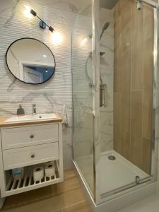 a bathroom with a shower and a sink and a mirror at Apartment Insat II in Szczecin