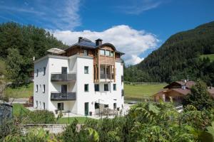 ein großes weißes Gebäude mit einem Holzdach in der Unterkunft Alpin Sport in St. Ulrich in Gröden