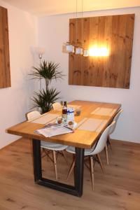 un tavolo da pranzo in legno con sedie bianche e lampadario di Isartaler Hoamat Haus a Mittenwald