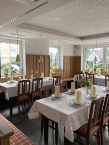 a dining room with white tables and chairs and windows at Platzwirt in Unterschneidheim