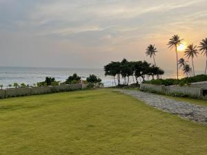 a grassy field with palm trees and the ocean at Apartment L4-5, Oceanfront Condos, Galle, Sri Lanka in Galle