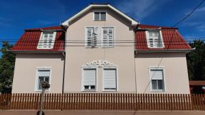 une maison blanche avec un toit rouge et une clôture dans l'établissement Villa Napsugár, à Balatonlelle