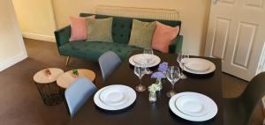 uma sala de jantar com uma mesa e um sofá verde em The Fenton Lodge em Fenton