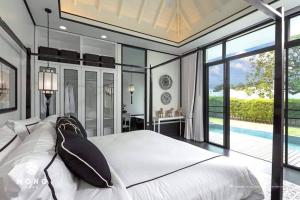 una camera da letto con un grande letto bianco con cuscini neri di MONO LUX Villa x MonthStayZ Thailand a Chalong