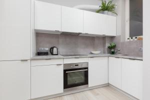 una cocina blanca con armarios y electrodomésticos blancos en City Center Apartments Hoża by Renters, en Varsovia