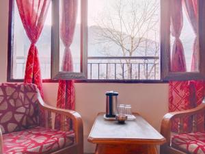 una camera con tavolo, sedia e finestre di Hotel River INN a Manāli