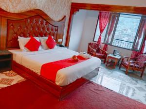 a bedroom with a large bed with red pillows at Hotel River INN in Manāli