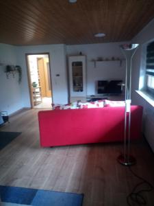 a living room with a red couch and a lamp at Ferienwohnung im idyllischen Neckartal in Starzach