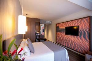 a hotel room with a bed and a tv on a wall at Panafrica Hotel Boutique & Spa in Bata