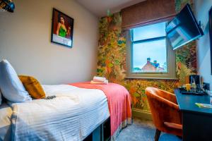 a room with a bed and a desk and a window at The Crown Hotel in Glastonbury