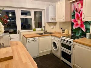 a kitchen with white cabinets and a washing machine at Custard creams cottage in Knaresborough