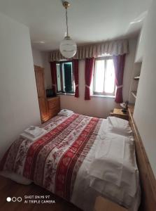 1 dormitorio con 1 cama grande con manta roja en La Favorita, en Lozzo Cadore