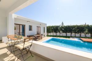 a patio with a table and chairs next to a swimming pool at Napa Sunlight Villa #1 in Ayia Napa