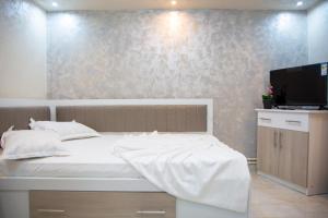 a bedroom with a white bed and a flat screen tv at CASA ALESIA SI ERIC in Jiblea Veche