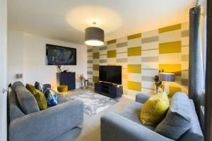 a living room with two couches and a television at Stunning 4 Bed House with Cinema Room & Parking in Manchester