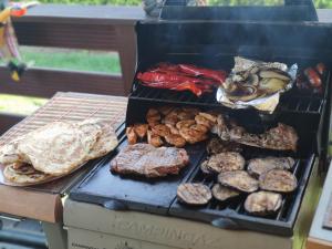 a grill with meat and other food on it at Dom wakacyjny nad jeziorem - Willa Mira in Zarzecze