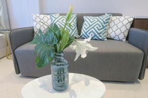 a vase with flowers on a table in front of a couch at Comfy Studio 7 by ReCharge in Singapore