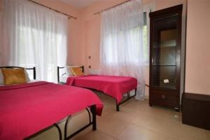 a bedroom with two beds with red sheets and a window at Villa Alekos in Limenas