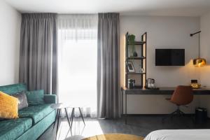 een woonkamer met een groene bank en een bureau bij Ariane Hotel in Ieper