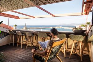 a man sitting in a chair on a deck looking out at the ocean at Domus Renier Boutique Hotel in Chania Town