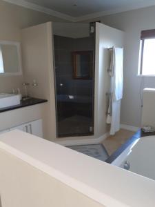 a white bathroom with a tub and a sink at Brighton Bay in St Francis Bay