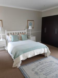 a bedroom with a large white bed with blue pillows at Brighton Bay in St Francis Bay