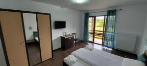 a room with a bedroom with a bed and a mirror at Popasul din Lunca in Pui