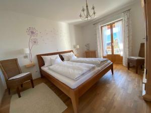 a bedroom with a bed and a chair and a window at Ferienwohnung Hermann in Fischbachau