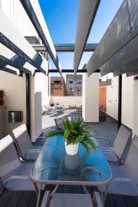 a balcony with a glass table and chairs at 8 lacus in Hospitalet de Llobregat