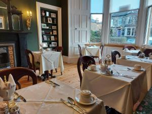 ein Restaurant mit Tischen und Stühlen mit weißem Tischtuch in der Unterkunft Barony House in Edinburgh