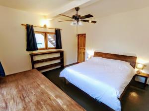 1 dormitorio con cama blanca y ventilador de techo en Blue Planet Dive Resort en Bira