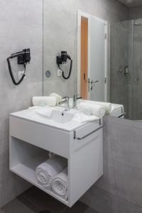 a bathroom with a white sink and a mirror at Meu Hotel Porto Gandra in Paredes