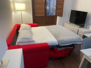 1 dormitorio con cama roja y TV de pantalla plana en Apto Turístico Plaza del Mercado 1.2, en Salamanca