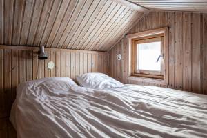 a bed in a wooden room with a window at Hyttgårdens stugby i Huså, Åre kommun in Järpen