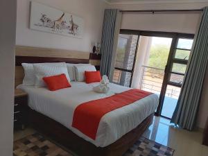 1 dormitorio con 1 cama grande con almohadas rojas y blancas en Top Stay Inn, en Kasane