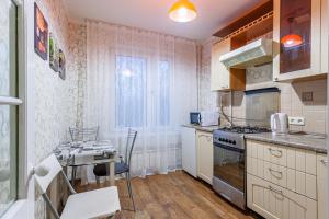 Il comprend une cuisine équipée d'une cuisinière et d'une table. dans l'établissement Economy Brusnika Apartment Vykhino, à Moscou