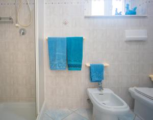 a bathroom with a toilet and a shower and blue towels at Lungomare Bay, e sei in spiaggia... in Cala Gonone