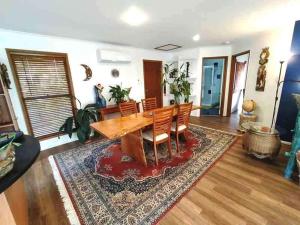 a living room with a wooden table and chairs at Cosy Romantic Cottage in Tallebudgera