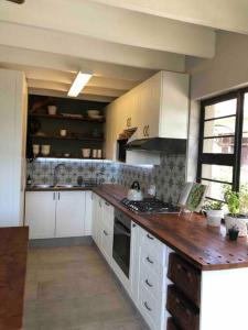 a kitchen with white cabinets and a wooden counter top at Loft on Honey in Sunridge Park