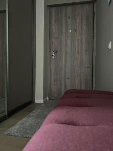 a bedroom with a bed and a wooden door at Blue Peony in Druskininkai