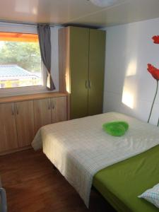a bedroom with a bed with a green pillow on it at Mobile home Sea Jezera Village, otok Murter in Tisno
