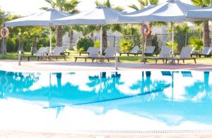 a swimming pool with chairs and umbrellas next to a pool at Aktaion Resort in Gythio