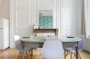 a dining room with a table and white chairs at NOCNOC - Le jardin du prefet in Lille