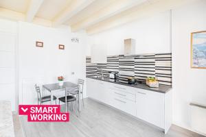 uma cozinha com armários brancos e uma mesa de jantar em Borgo Gasparina Apartments by Wonderful Italy em Castelnuovo del Garda