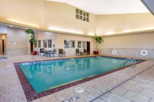 a swimming pool in a hotel with a table and chairs at Comfort Inn Bentonville - Crystal Bridges in Bentonville