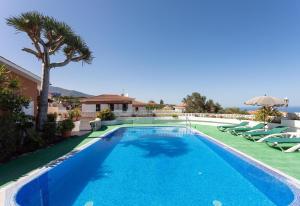 une piscine avec des chaises longues et une villa dans l'établissement Parque Las Flores, à Puerto de la Cruz