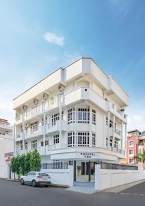 a white building with a car parked in front of it at Poshtel VNS in Varanasi